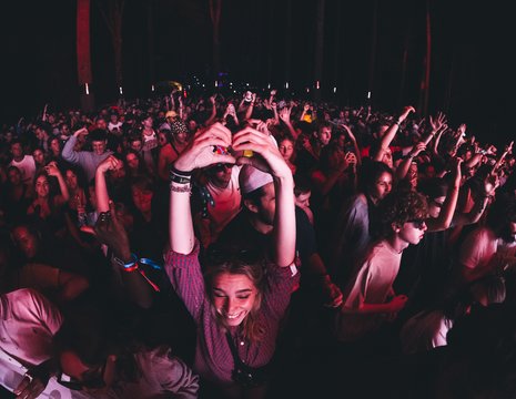 Femme fait un coeur avec ses mains dans une foule de personnes